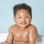 Baby laughing with bubbles during splash clean-up, West Sussex cake smash and splash