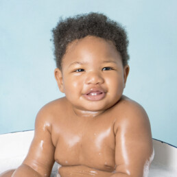 Baby laughing with bubbles during splash clean-up, West Sussex cake smash and splash