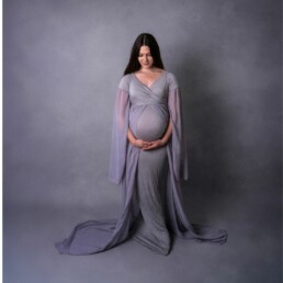 mother proudly holding her pregnancy bump in a floaty dress with bump covered