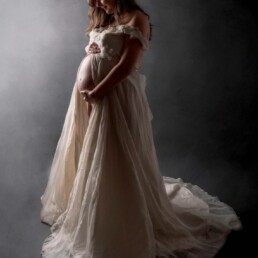 mother proudly holding her pregnancy bump in a floaty dress
