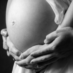 mother and fathers hand together around the bump of a baby yet to be born