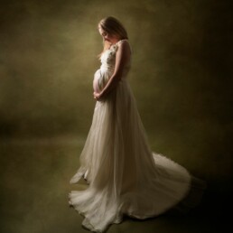 mother proudly holding her pregnancy bump in a floaty dress