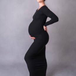 mother proudly holding her pregnancy bump in a black tight fitting dress