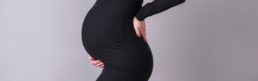 mother proudly holding her pregnancy bump in a black tight fitting dress